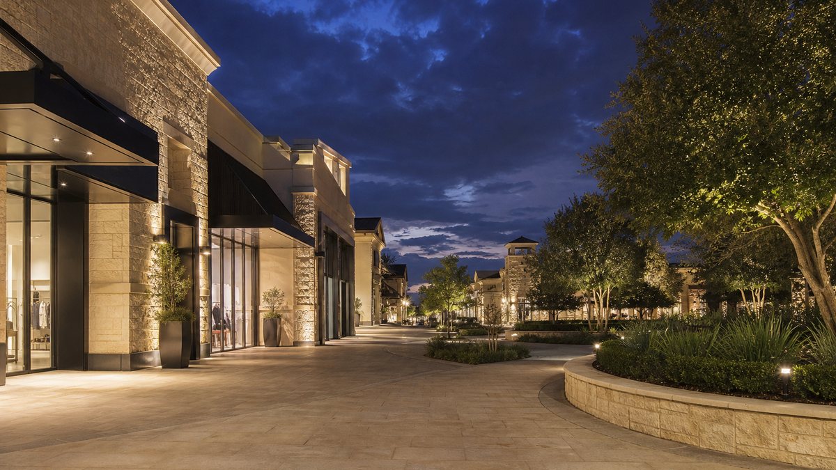 Open-air shopping center in Highland Village Texas with LED storefront canopy and walkway lighting at dusk