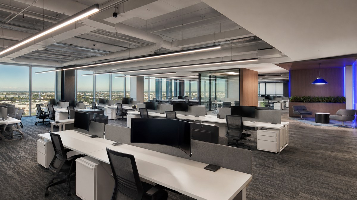 Open office floor on a Plano corporate campus with low-glare LED linear lighting and daylight dimming near windows